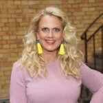 Barbara Schöneberger mit blonden Locken und rosa Kleid lächelt in die Kamera