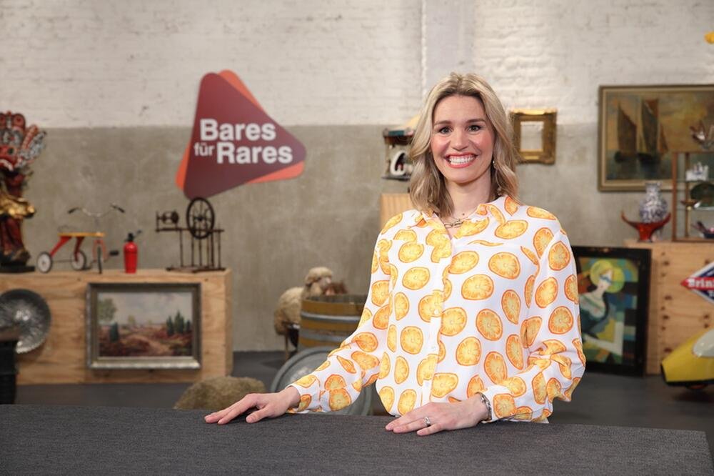 Dr. Bianca Berding, Expertin bei „Bares für Rares“, lächelnd im ZDF-Studio vor Antiquitäten und dem Sendungslogo